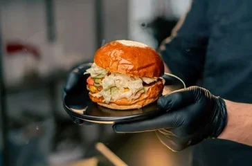 Chef serving a gourmet burger on a black plate