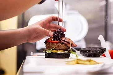 Chef preparing a gourmet burger with fresh ingredients